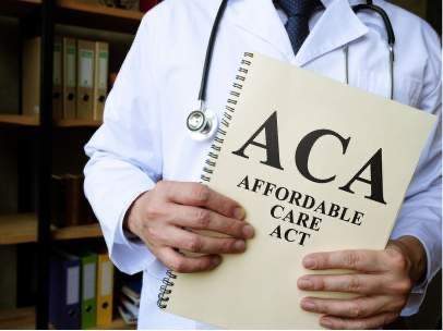 A doctor wearing a stethoscope holding a booklet titled, ACA Affordable Care Act